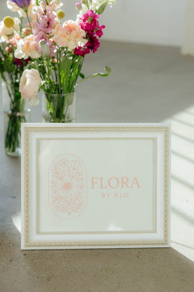 Flora by Klo logo sign with fresh flowers in vases