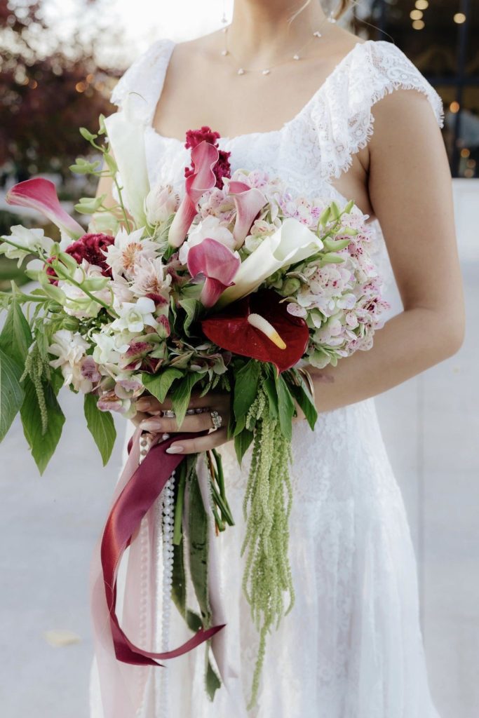 Bride holding a cascading burgundy and blush bouquet with ribbon