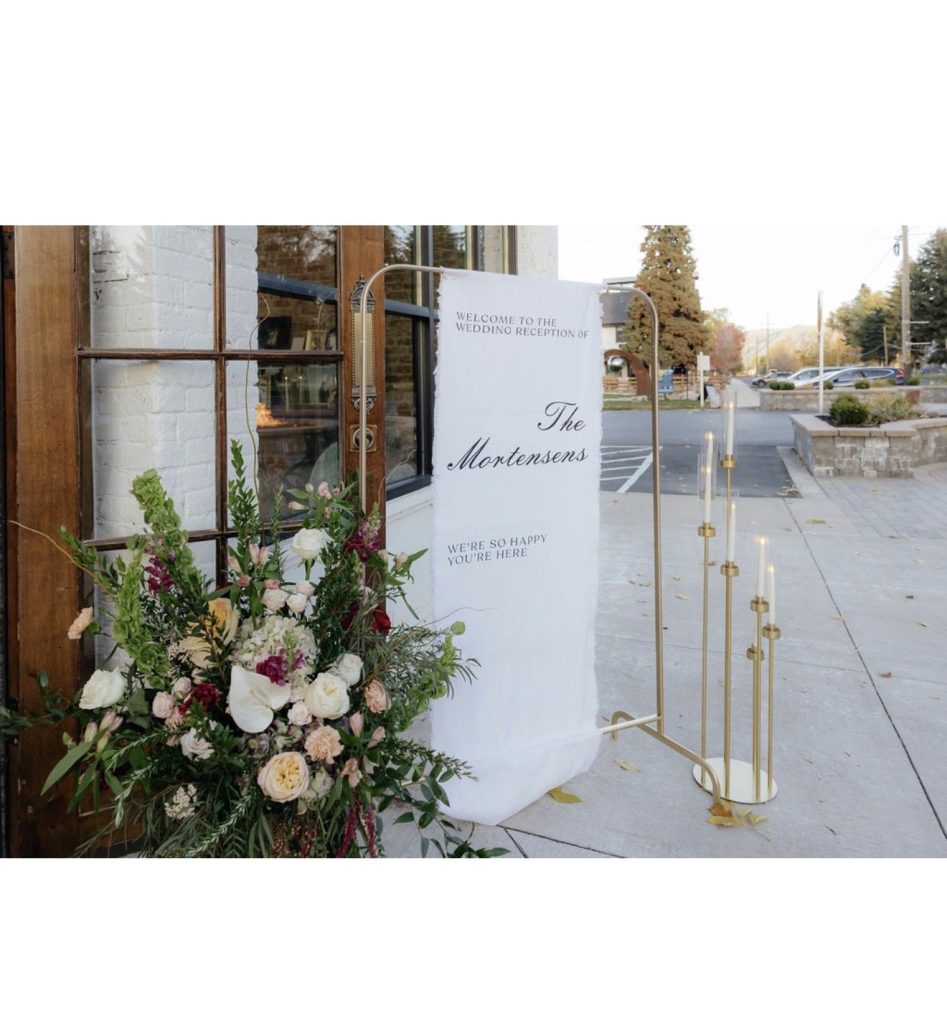 Wedding welcome sign with a floral arrangement at the base