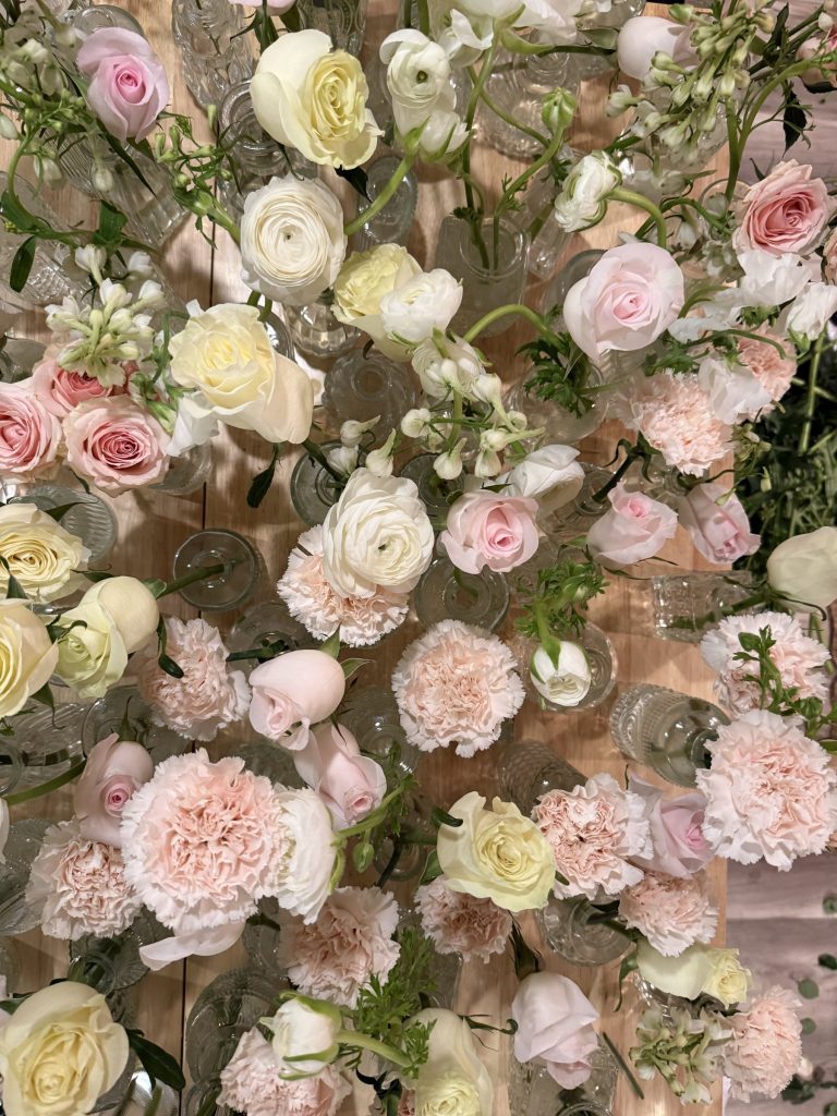 Dense installation of blush and cream garden roses and carnations