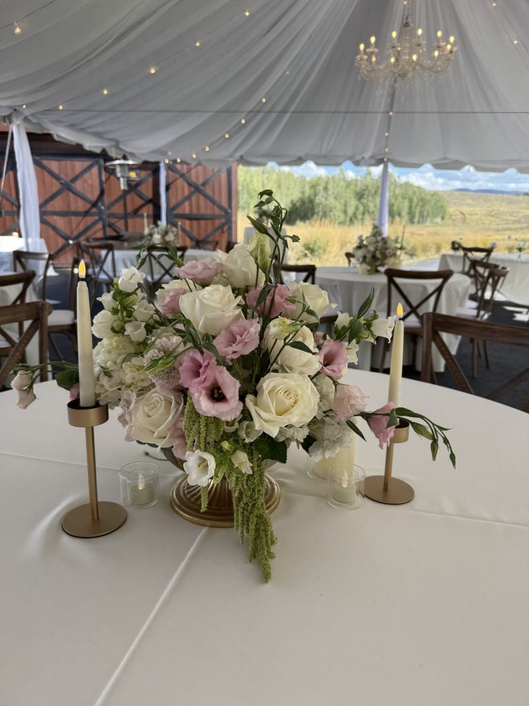 Tented reception table with a blush and white centerpiece and candles
