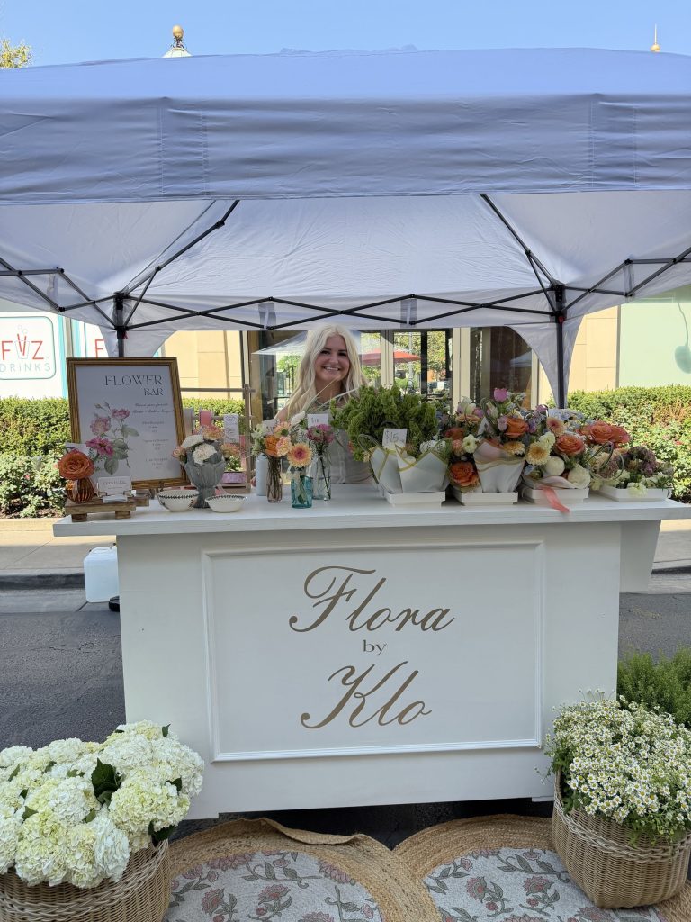 Kloe Brown behind the Flora by Klo flower cart at an outdoor pop-up